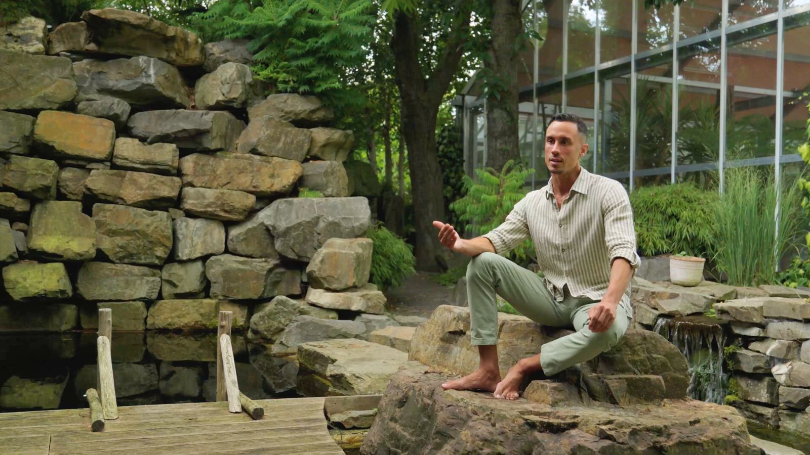 Still from the film: Jonathan Ramalho sitting on rocks beside a pool, speaking to camera